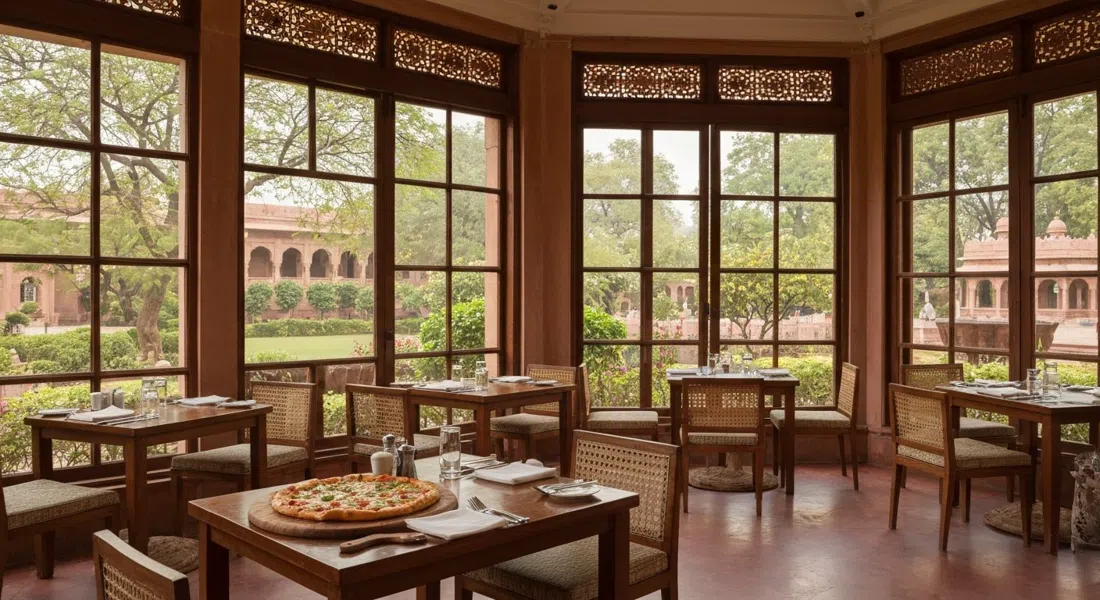 the garden-facing dining room at Trident Agra, wood-fired pizza and leafy hotel gardens beyond the windows in soft afternoon light