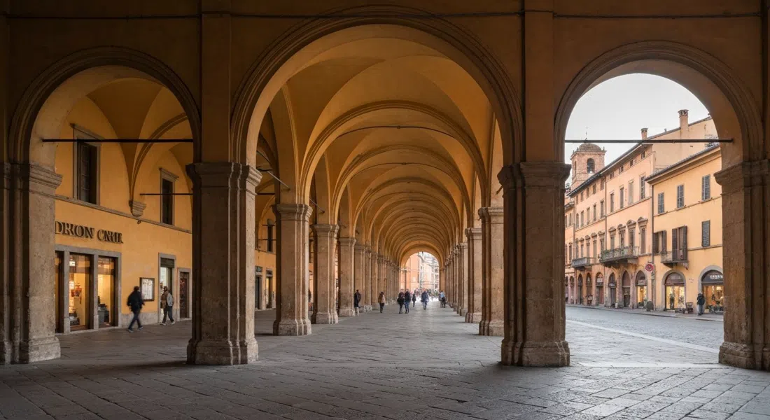 the Portico di San Luca receding in a long ochre tunnel of arches from Porta Saragozza, early morning light and empty pavement