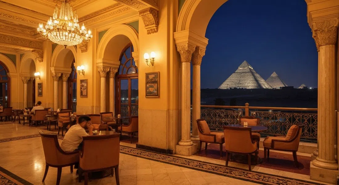 the Sultan Lounge at Marriott Mena House at night, warm light on gilded interiors with the illuminated pyramids visible through the windows