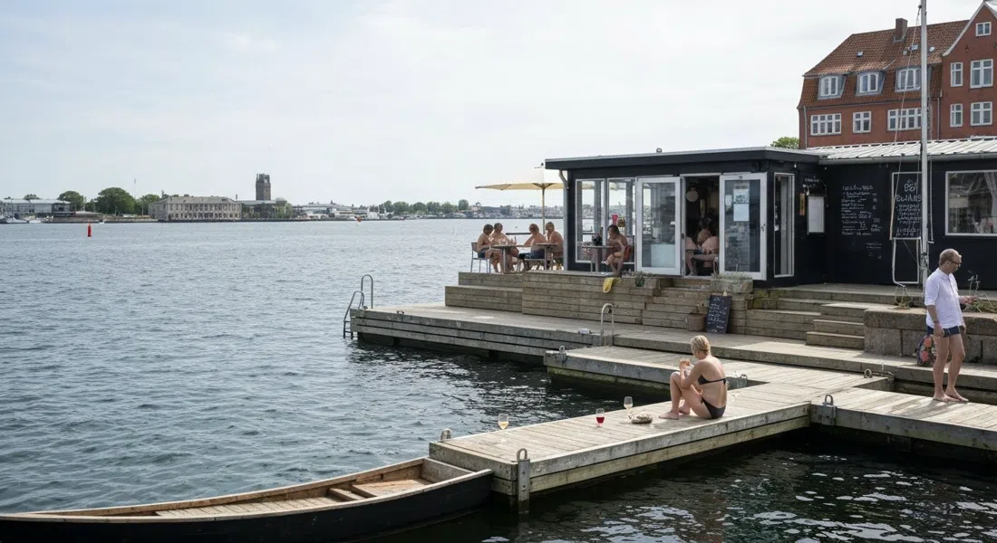 La Banchina’s small boathouse terrace and swim pier at the harbour edge, with a few guests in swimwear and glasses of natural wine