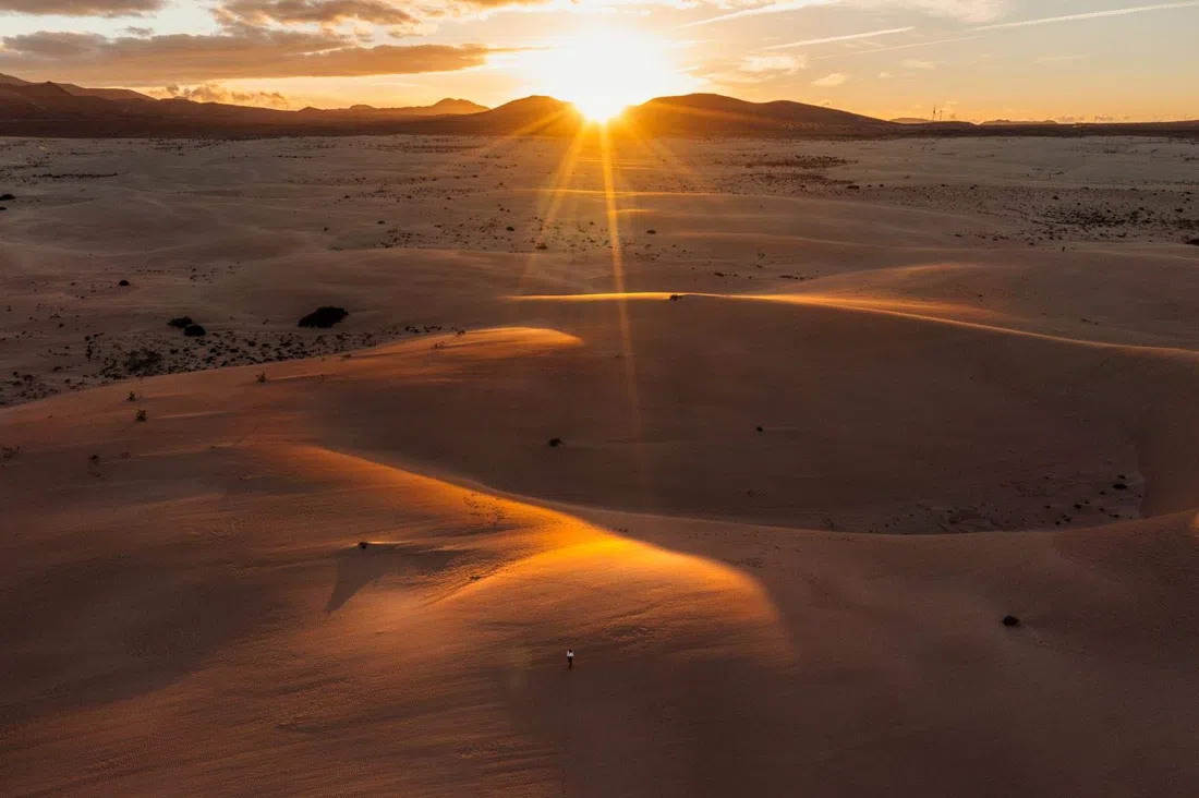 the pale dunes of the Parque Natural de Corralejo rolling south toward the red cone of Montaña Roja