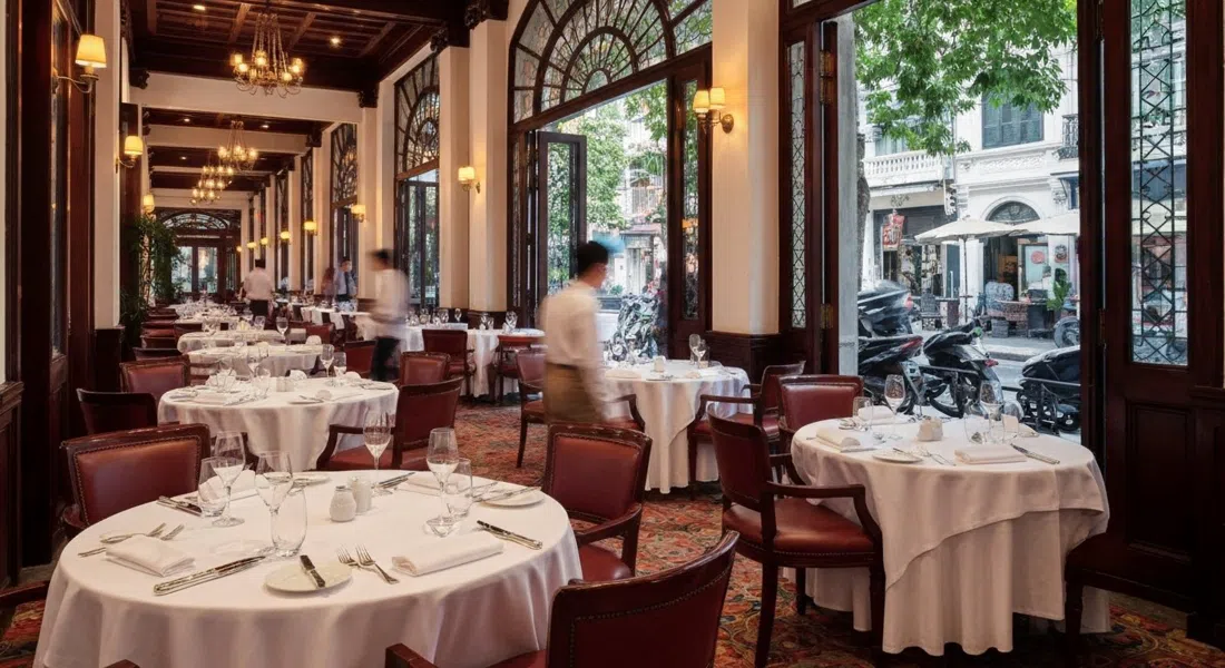 Le Beaulieu’s elegant dining room inside the Metropole, white linens, polished glassware and warm colonial lighting evoking old Hanoi fine dining