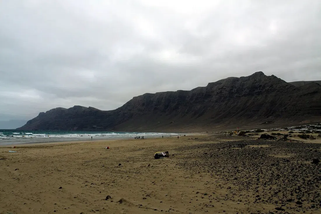the 6km arc of sand at Famara beach with the Risco de Famara cliff rising behind it