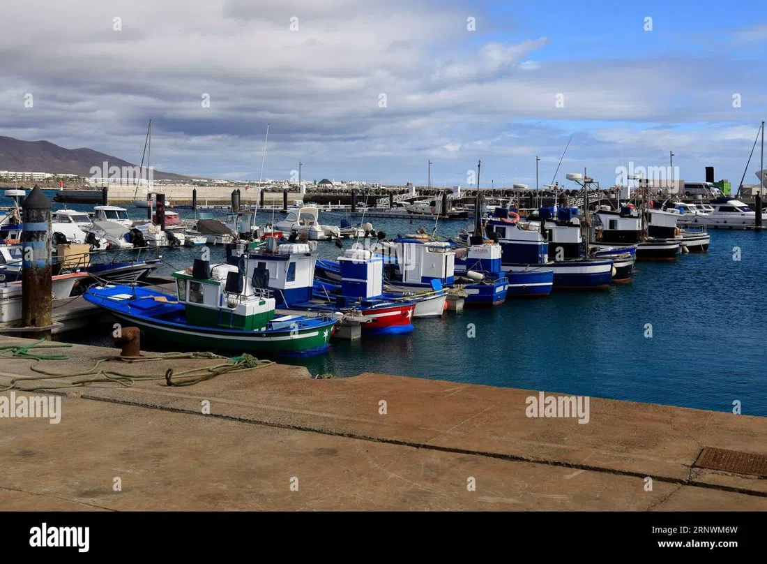 the working fishing harbour in the old town of Playa Blanca, small boats tied up with the seafront promenade behind