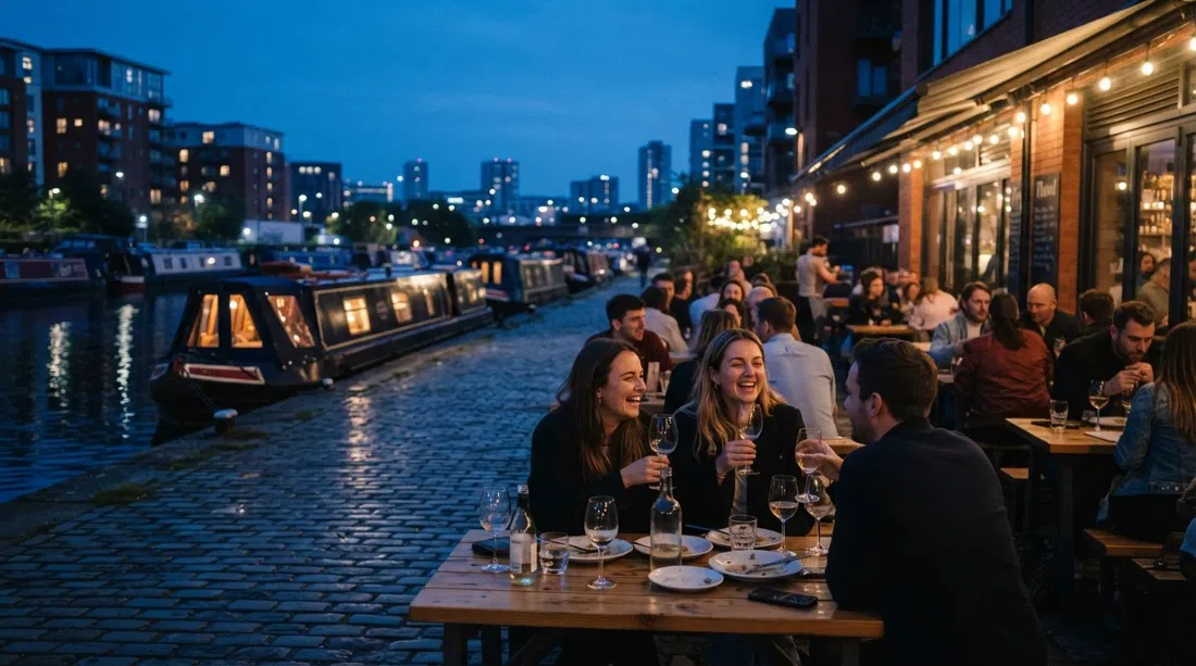 the terrace at Flawd on New Islington Marina at blue hour, wine glasses on tables and canal boats moored beside the water