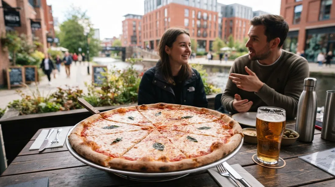 a giant New York-style pizza at Nell’s in Kampus, with a craft beer on the table and the canalside garden blurred behind