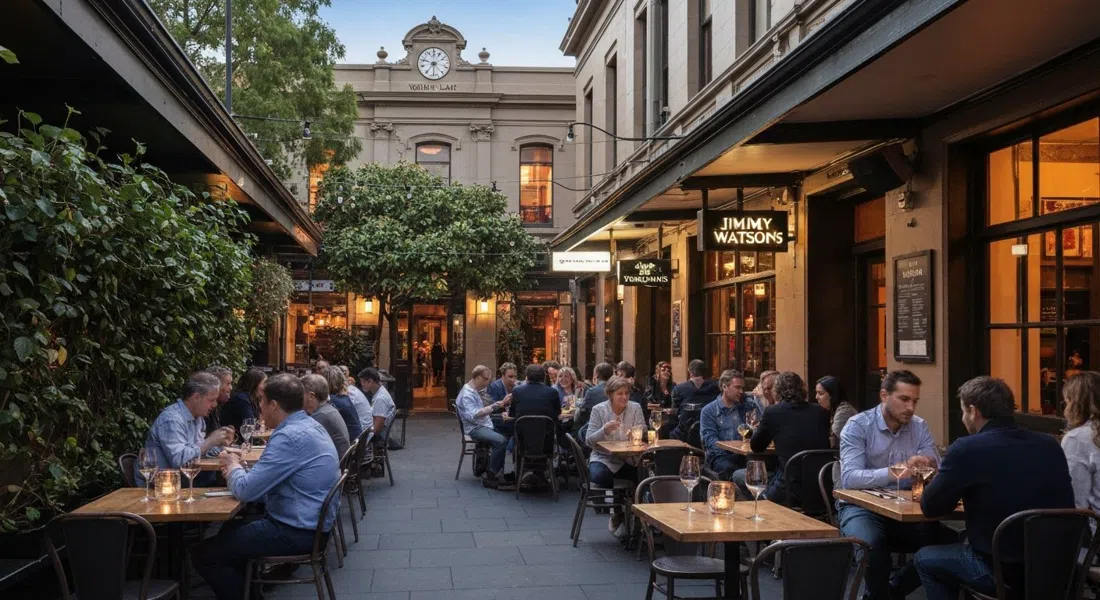 Jimmy Watson’s leafy courtyard on Lygon Street at dusk, wine glasses on tables with the Wolf’s Lair rooftop visible above