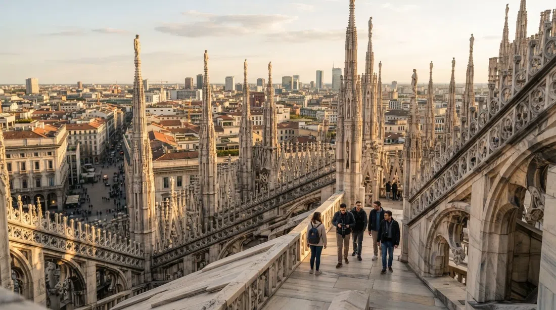 the Duomo di Milano rooftop terraces at late afternoon, marble spires and flying buttresses seen from above with the city stretching out beyond