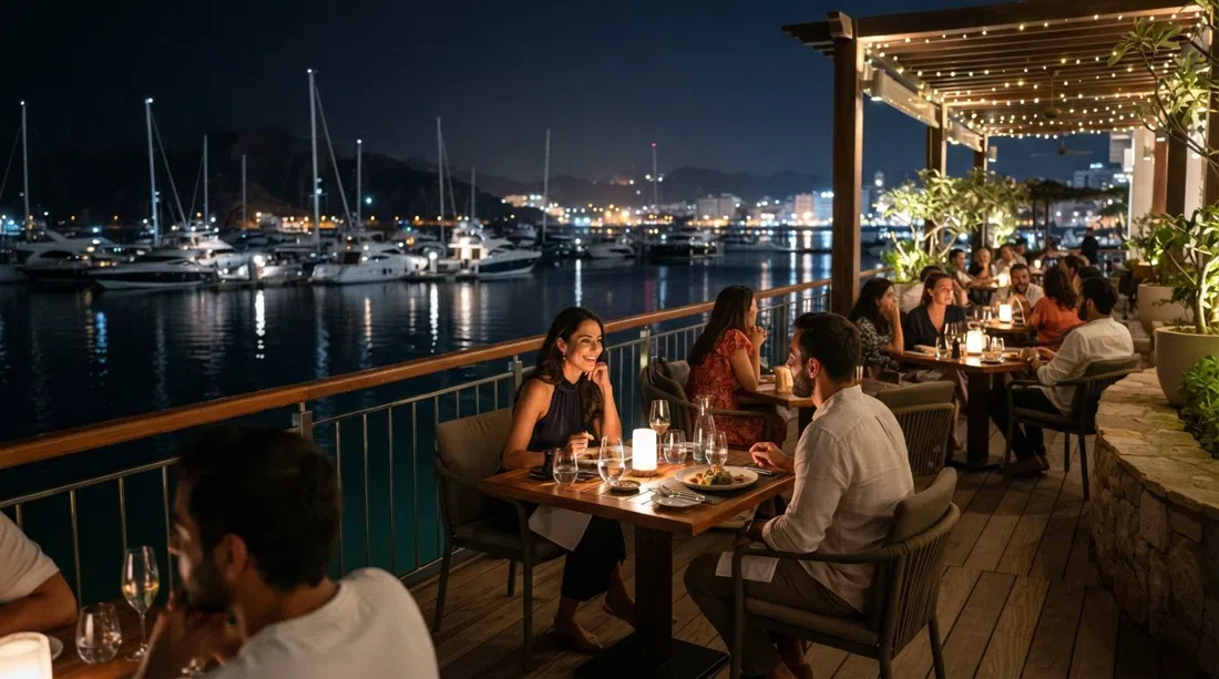 Huqqa’s marina-side terrace at night, tables lit over the water with yachts and reflections beyond