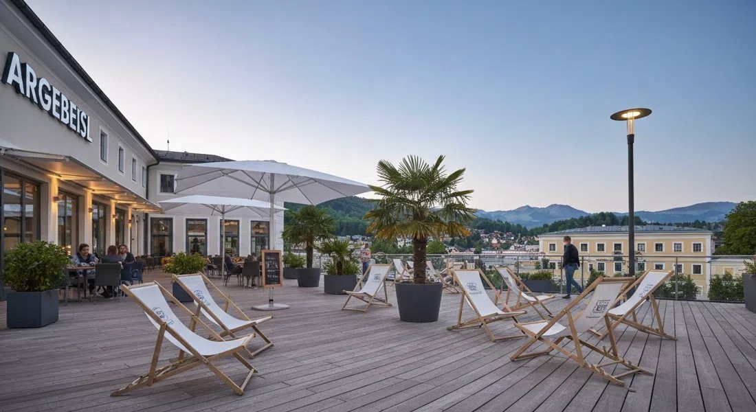 ARGEbeisl’s summer terrace with deckchairs and palms, evening light on the Unipark Nonntal campus atmosphere