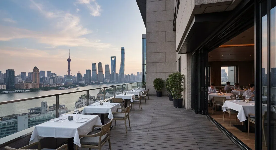 the terrace and dining room of Mr & Mrs Bund on the sixth floor of Bund 18, evening light over the Huangpu with skyline reflections beyond