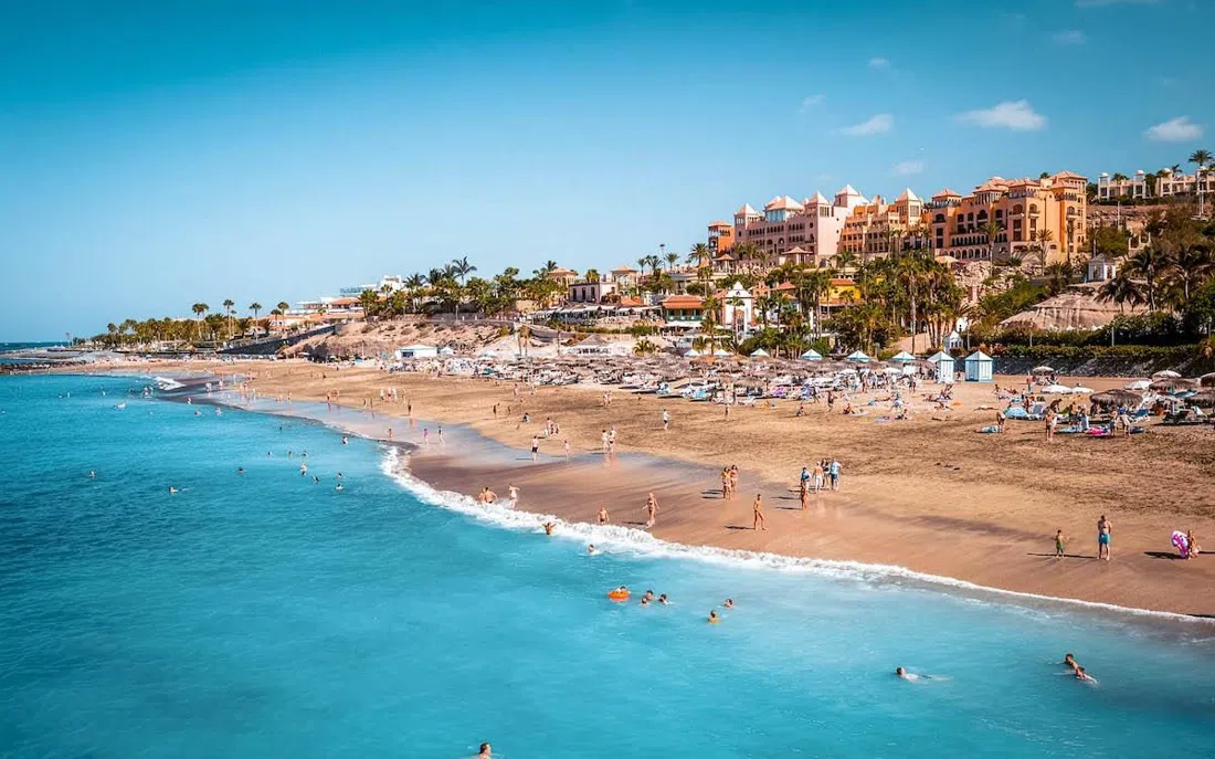 Playa del Duque beach in Costa Adeje, groomed sand and rows of sunbeds below the five-star hotels