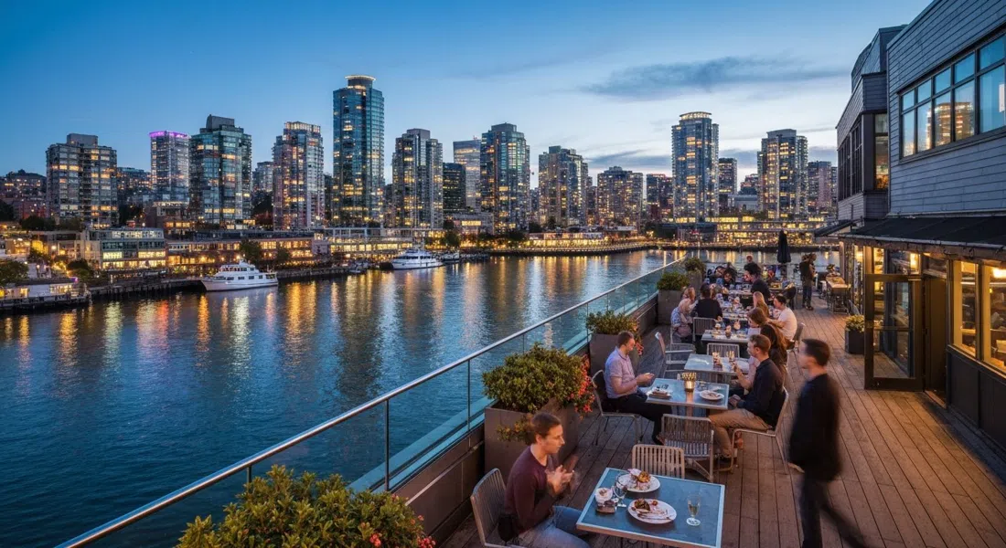 the Sandbar Seafood Restaurant rooftop patio at dusk, False Creek water below and downtown towers glowing across the channel
