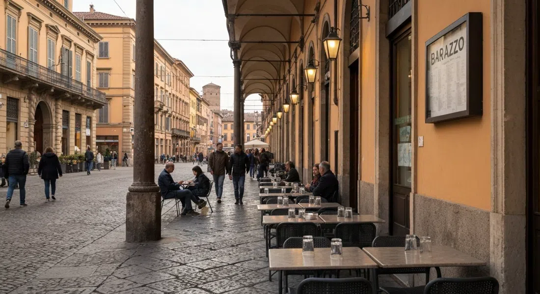 pavement tables at Barazzo on Via del Pratello in spring evening light, glasses on the tables and people watching from the curb under the porticoes