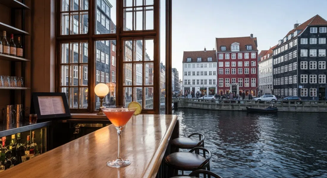 Ruby cocktail bar in an 18th-century townhouse at Nybrogade 10, warm evening light through the windows and a classic cocktail on the bar facing the canal