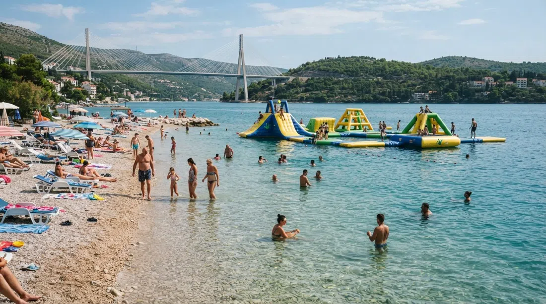 Copacabana Beach in Babin Kuk with shallow water, families, the floating Wibit inflatable water park and the Franjo Tuđman Bridge in the distance