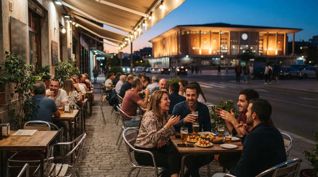 the evening terrace at Cervecería Ecu with locals lingering over cañas and oversized tapas, the Palacio de Deportes glowing across the street after sunset