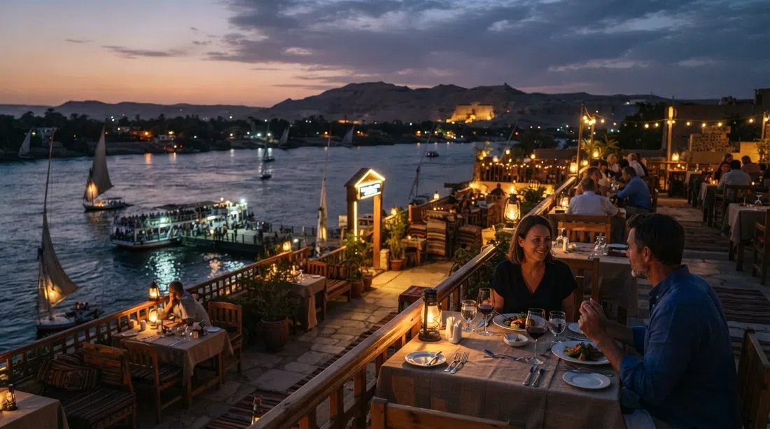 Sunflower Restaurant’s rooftop by the ferry dock at dusk, with the Nile below, tables set for dinner and the West Bank sky fading over the river