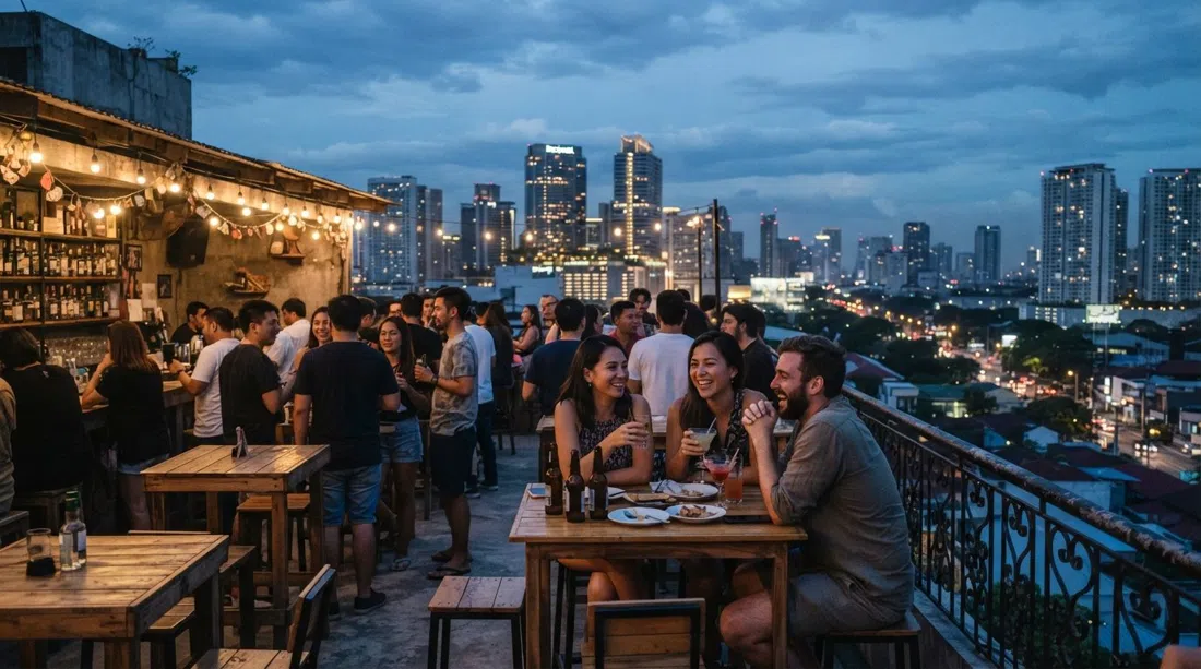 the Z Hostel Rooftop in Poblacion, Manila, at dusk, with a 360-degree view toward the Rockwell towers and the city lights coming on