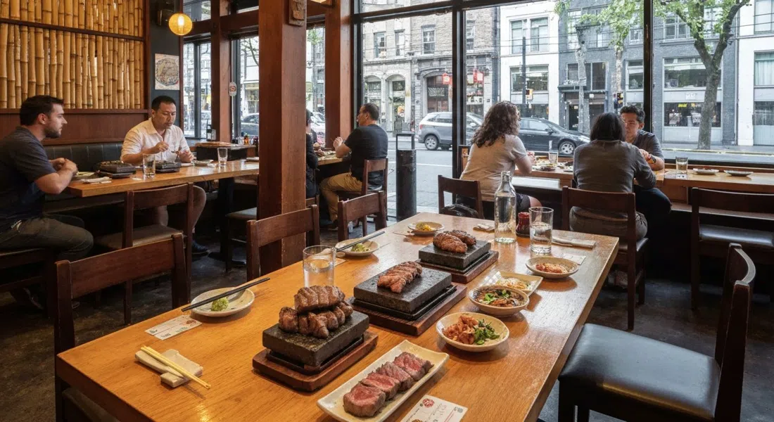 Kingyo Izakaya on Denman Street, a warm wood-and-bamboo dining room with stone-grilled beef and small plates on the table