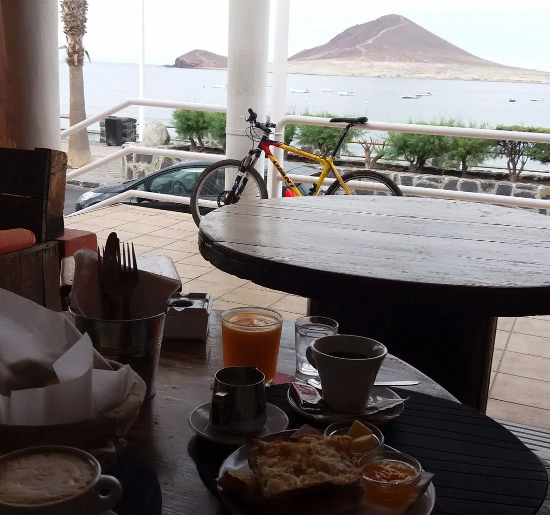 Manfred's Soul Café terrace in El Médano at sunset, with the surf crowd and Montaña Roja beyond